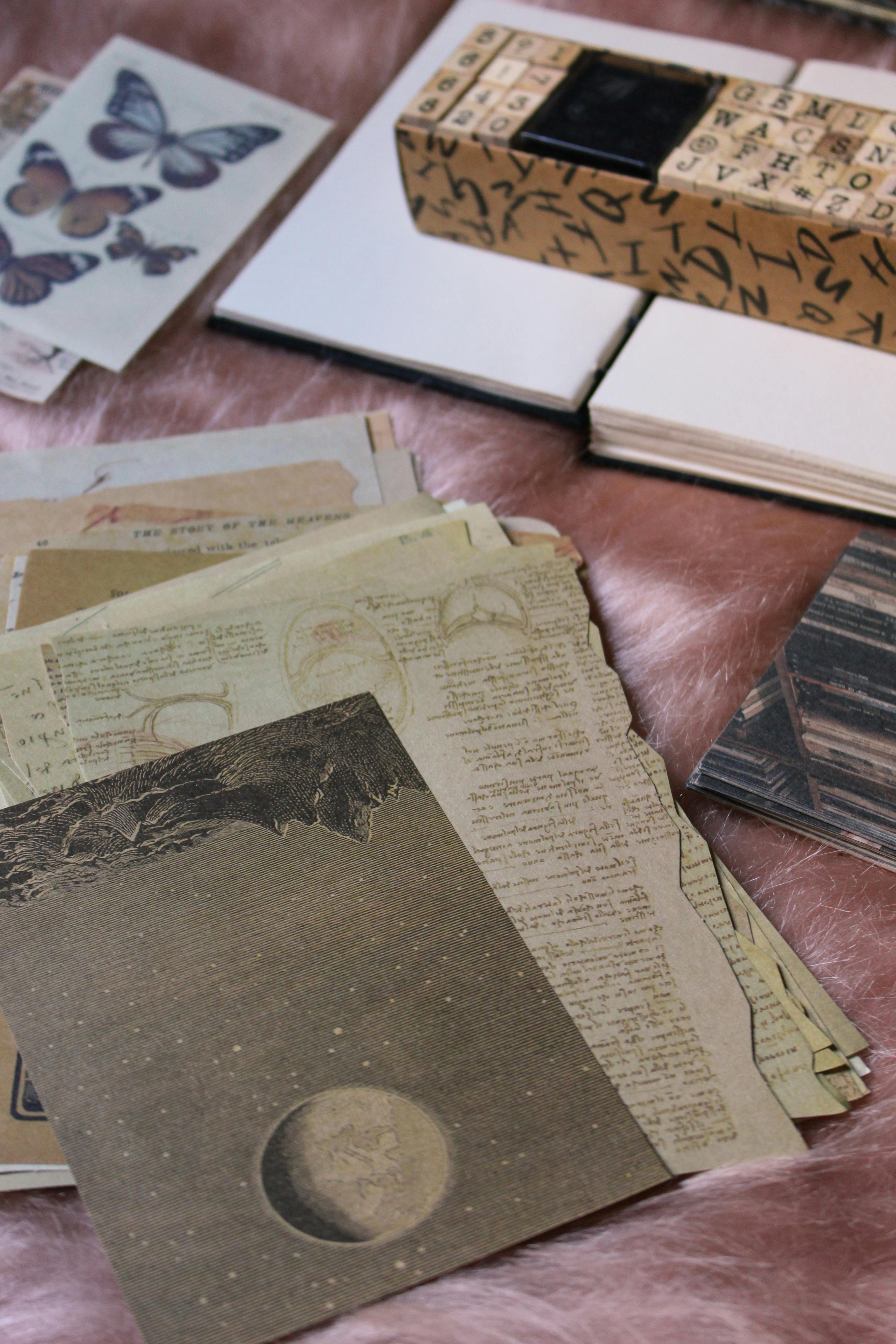 Vintage scrapbooking materials including patterned papers, cards, and alphabet stamps arranged on a desk